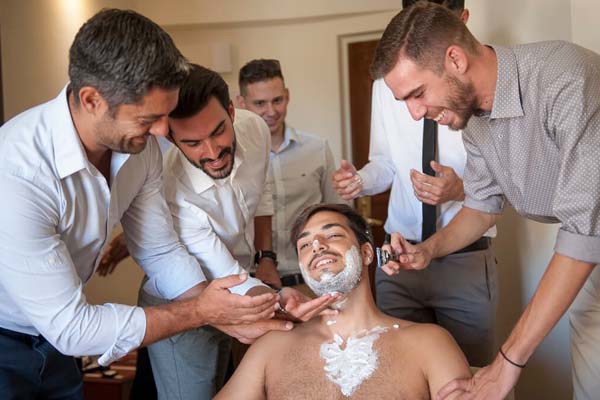 Friends shaving groom