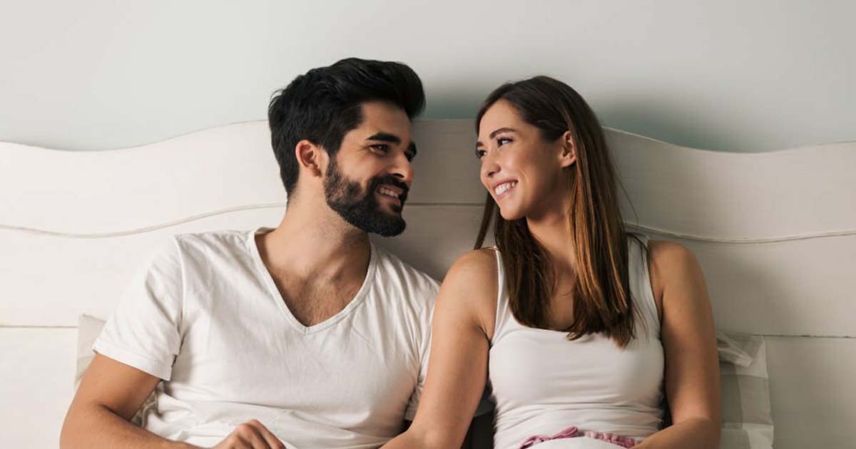 Happy couple communicating in bed in the morning stock photo