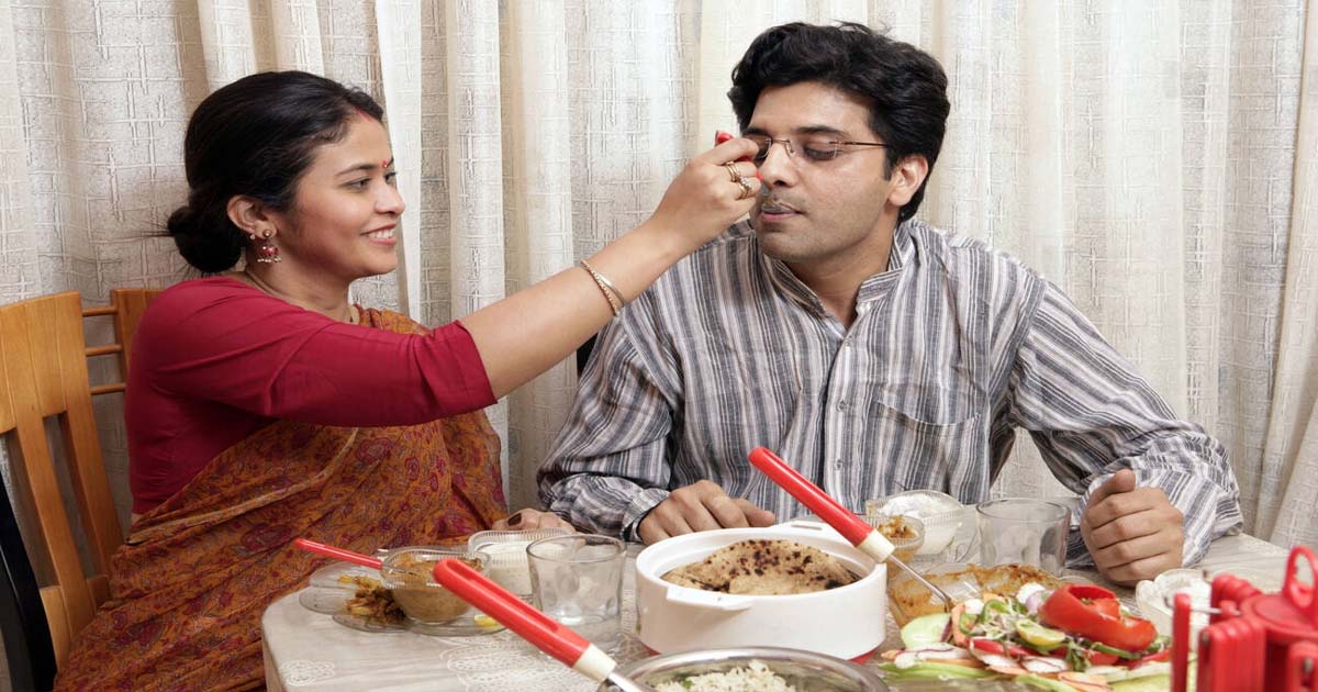 Wife feeding her husband at dining table